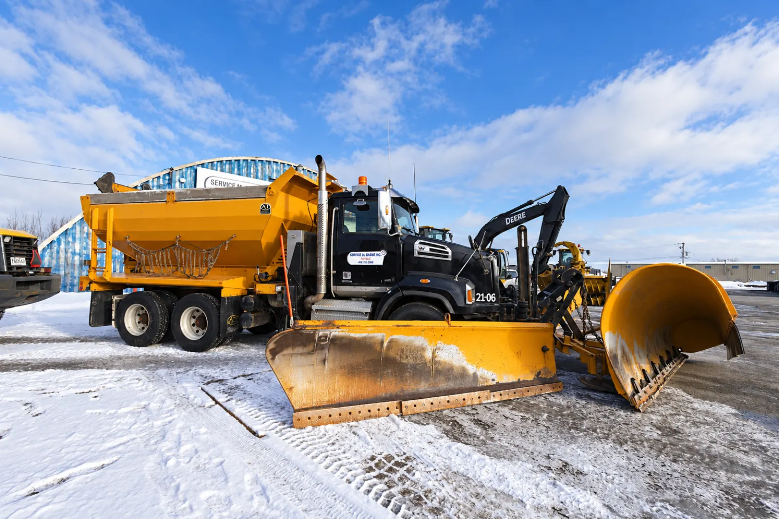 Camion de déneigement avec épandeur, gratte et aile de côté