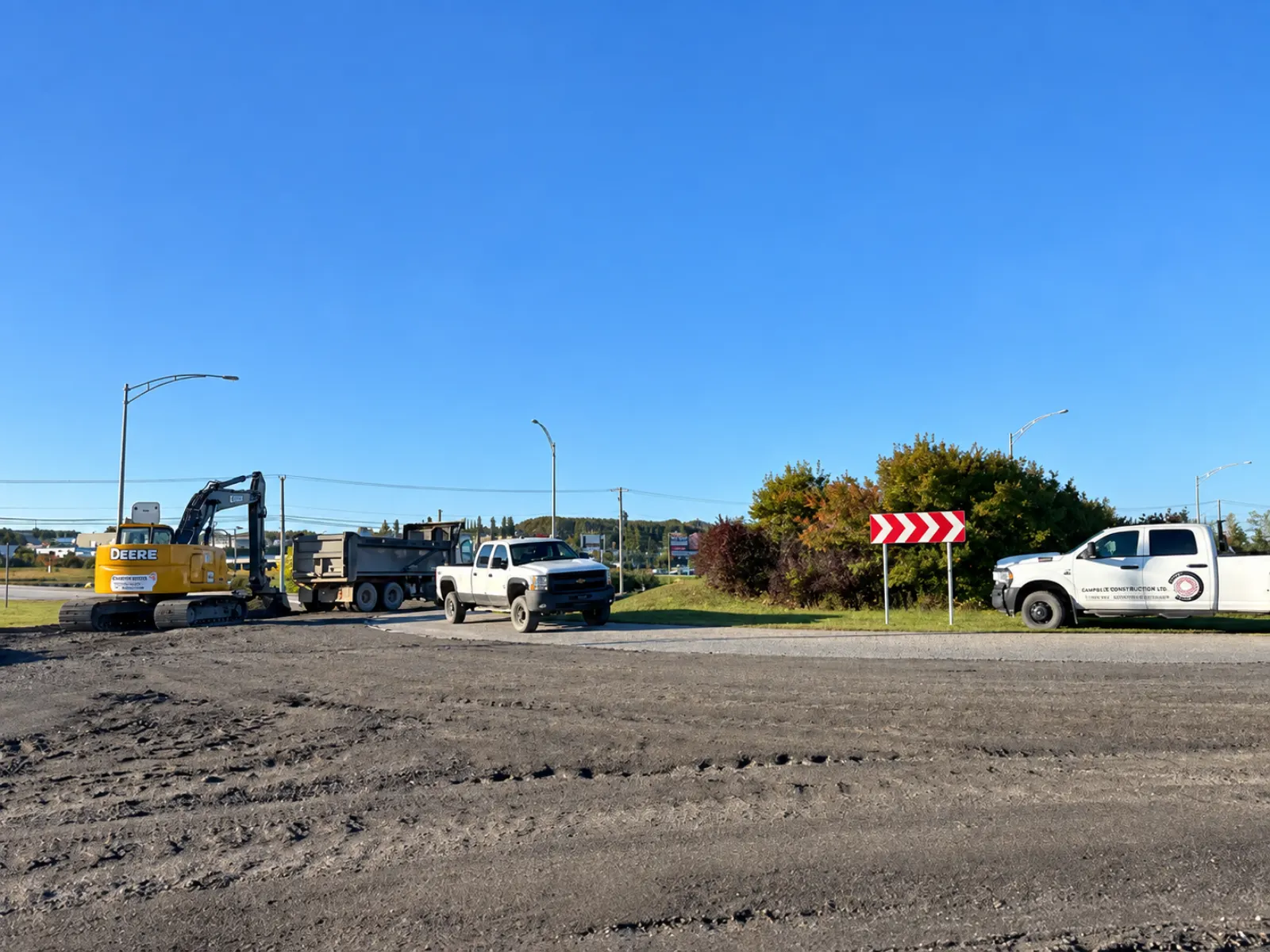 Réaménagement routier avec pelle mécanique et camionnettes de chantier