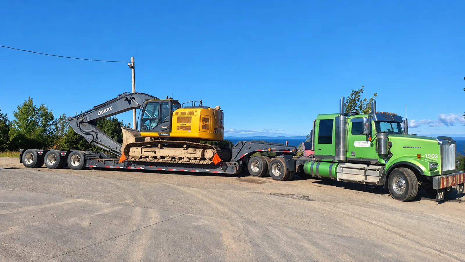 Pelle mécanique chargée sur un fardier tiré par un camion vert