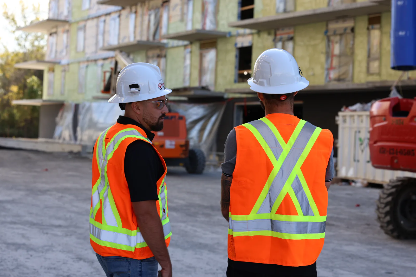 Deux intervenants SST observant un chantier résidentiel en construction